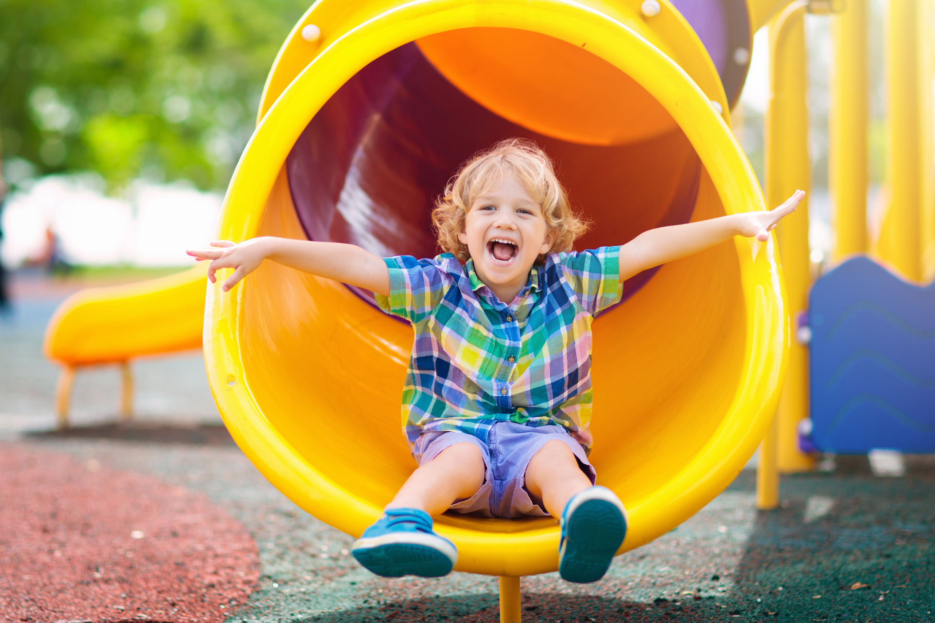 young boy on a yellow slide at the playground