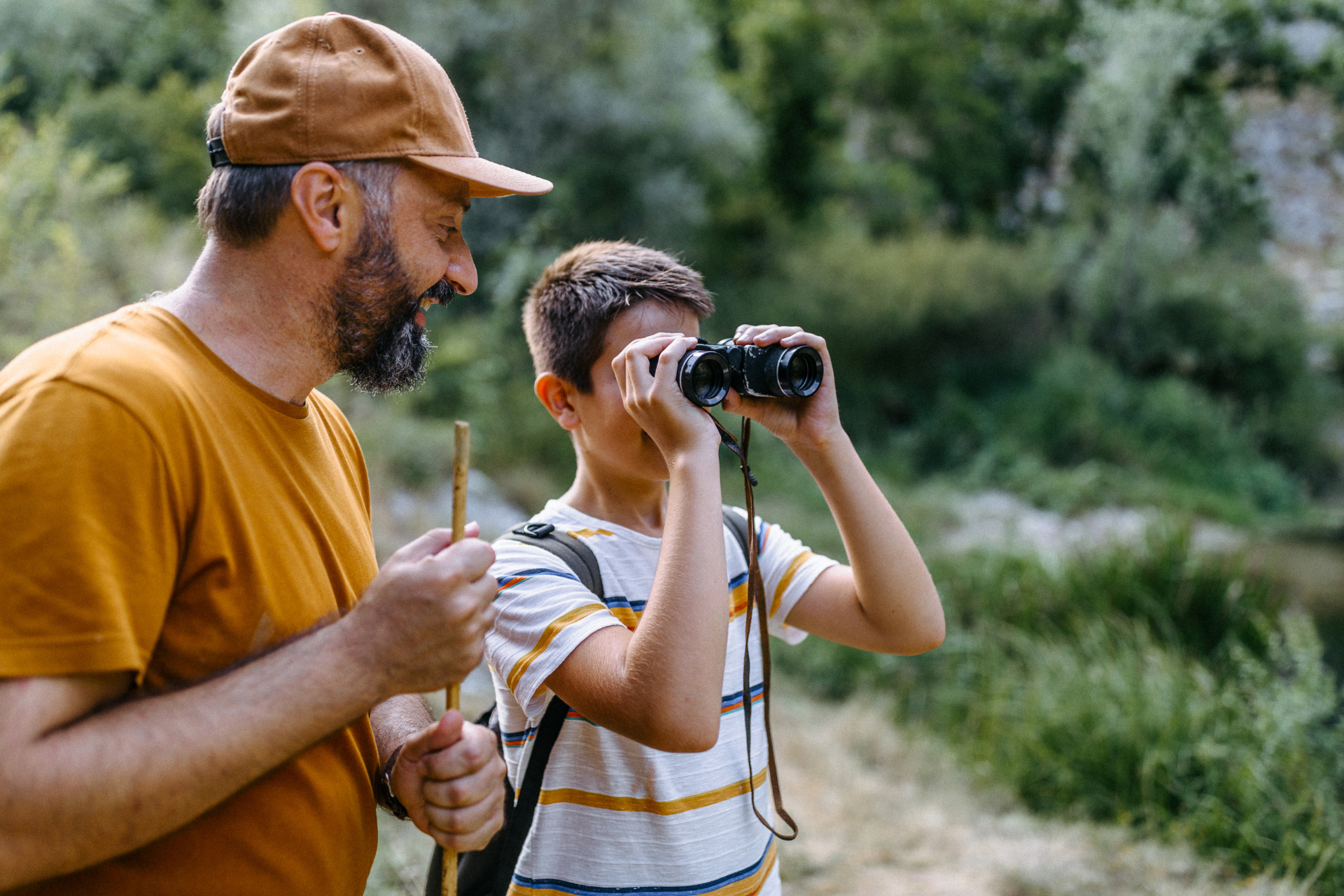child with binoculars in forest with father
