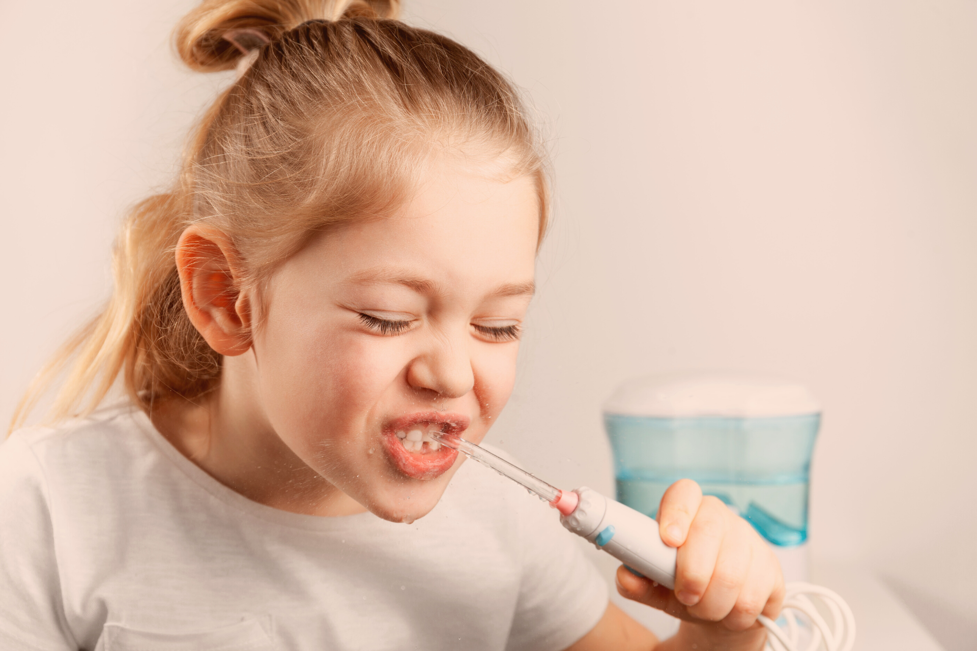 young girl using a water flosser